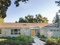 a house that has some plants in the front yard and trees on the other side