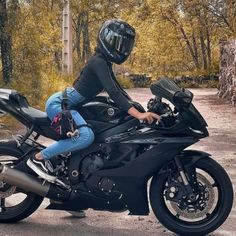 a person on a black motorcycle with a helmet sitting on the bike's seat