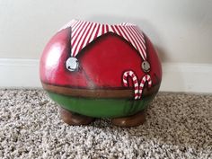 a red and green ceramic pig with candy canes on it's nose sitting on the carpet