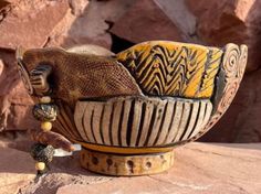 a yellow and black bowl sitting on top of a rock