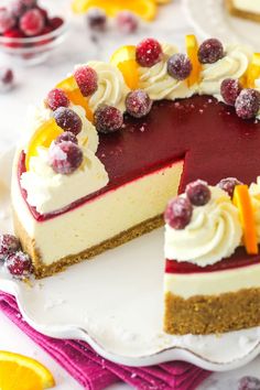 a cheesecake with berries and oranges on top sits on a white platter