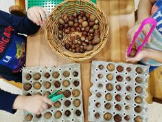 two children sitting at a table with trays of nuts and plastic utensils