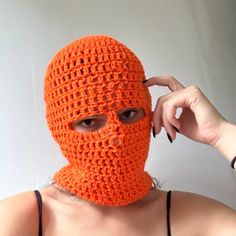 a woman wearing an orange crocheted mask