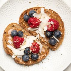 two french toasts topped with berries and coconut flakes on a white platter