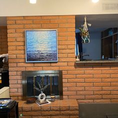 a living room with a brick fireplace and painting on the wall