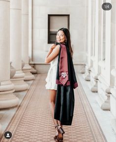 a woman standing in the middle of a hallway with her hand on her hip and smiling