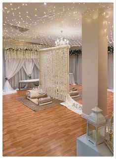 a room decorated in white with chandelier and pillows on the floor, surrounded by curtains