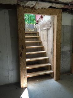 an open door leading to a set of stairs in a room with unfinished walls and flooring