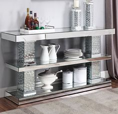 a mirrored shelf with dishes and cups on it in front of a painting hanging on the wall