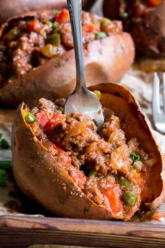 a fork in a baked potato that has been stuffed with meat and veggies