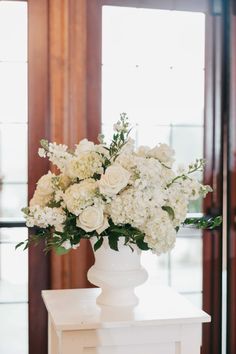 a white vase filled with flowers on top of a table