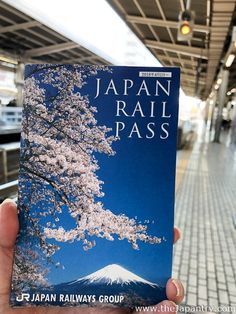 a person holding up a japanese rail pass book