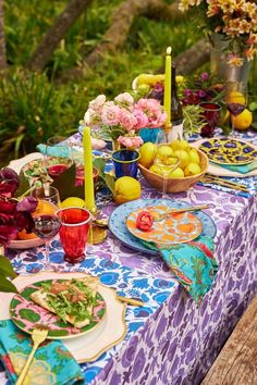 the table is set with colorful plates and place settings for an outdoor dinner or party