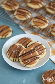 cookies with chocolate drizzled on them sitting on a plate next to cooling racks