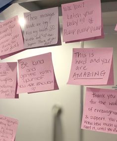 pink sticky notes attached to a wall with words written on them and hanging from the ceiling