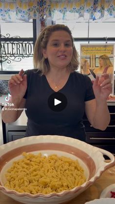 a woman standing in front of a bowl of pasta