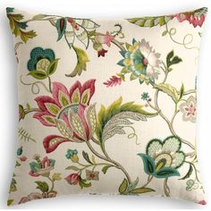 a white pillow with colorful flowers and leaves on the front, sitting on a white surface