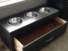 three bowls are placed in the bottom drawer of a dog bowl stand that is made out of wood and steel