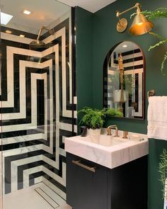 a white toilet sitting under a bathroom mirror next to a black and white tiled wall