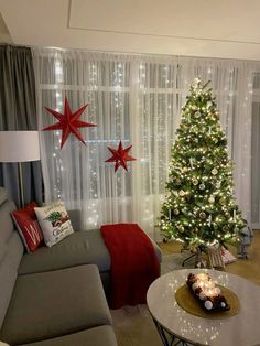 a living room with a christmas tree in the corner and two red stars on the wall