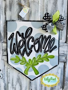 a welcome sign hanging on the side of a wooden door with polka dots and bows