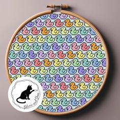 a cross stitch pattern with a black cat sitting on it's side in front of a wooden hoop