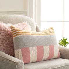 a chair with two pillows and a potted plant