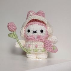 a small crocheted stuffed animal holding a flower in it's right hand