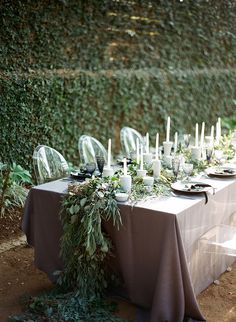 a long table with candles and greenery on it