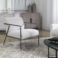 a living room with a white chair and a black coffee table in front of a painting