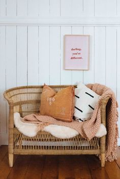 a wicker couch with pillows on it in front of a white paneled wall