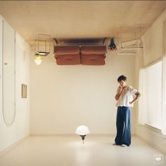 a man standing in an empty room talking on his cell phone and looking at something hanging from the ceiling