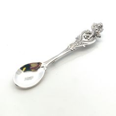 a silver spoon with an ornate design on the side and a flower in the middle