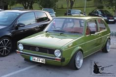 a green car parked next to other cars in a parking lot