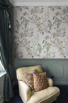 a chair with pillows in front of a floral wallpapered wall and blue carpet