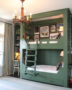 a green bunk bed in a room with pictures on the wall and a chandelier