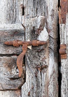 an old wooden door with rusted metal latches