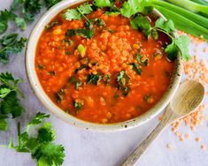 a white bowl filled with beans and cilantro on top of a table next to celery