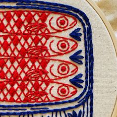 a close up of a red and blue embroidery on a piece of cloth that has been stitched