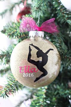 a christmas ornament hanging from a tree with pink ribbon and purple bow on it