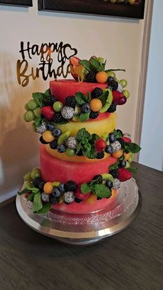 a three tiered cake decorated with fruit and the words happy birthday written on top