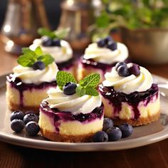 blueberry cheesecakes with whipped cream and fresh mint leaves on a silver plate