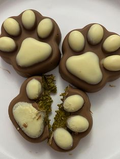 three pieces of chocolate with white frosting and paw prints on them sitting on a plate