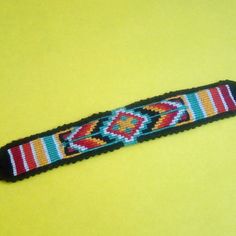 a beaded bracelet is sitting on a yellow surface with an orange and blue stripe