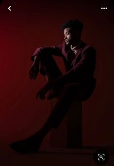 a man sitting on top of a wooden block in the middle of a dark room