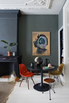 a dining room table with chairs around it and a painting on the wall behind it