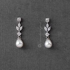 two pairs of earrings with pearls and diamonds on them, sitting on a gray surface