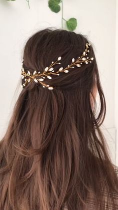 a woman with long brown hair wearing a gold leaf headpiece on top of her head