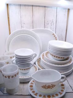 a table topped with lots of white and gold dishes