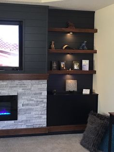 a living room with a television and fireplace in the corner, along with shelving